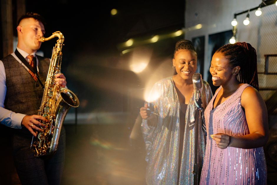 Vibrant night scene of a jazz band performing with saxophonist and singers enjoying the music.