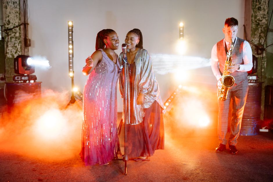 Energetic live jazz performance with two singers and a saxophonist on a smoky stage.