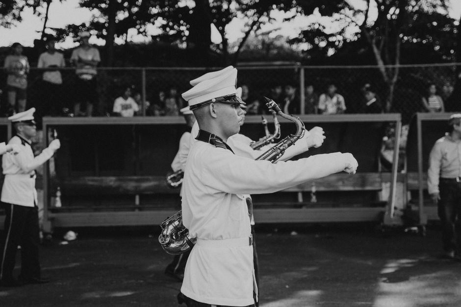 A dramatic black and white shot of a military band in uniform during a public outdoor event.