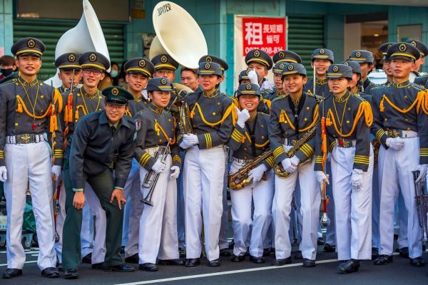 A Taiwanese marching band dressed in uniforms poses during an outdoor parade.