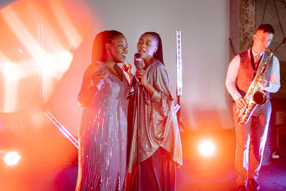 A vibrant live music performance with singers and a saxophonist under spotlights.