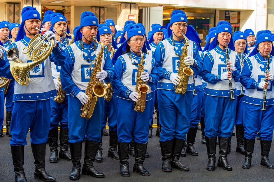A vibrant marching band performing in Taiwan, showcasing blue uniforms and brass instruments in an outdoor parade.