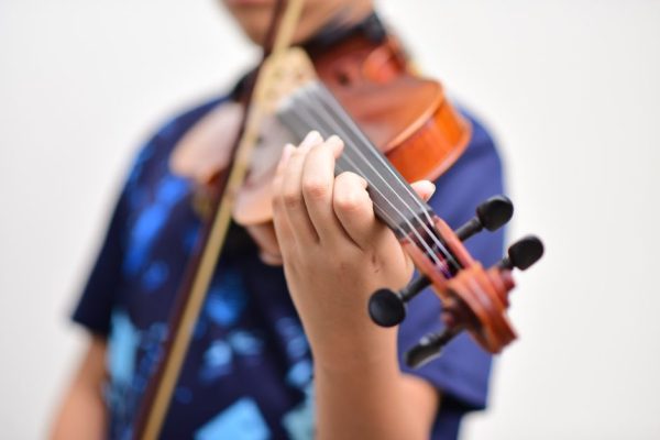A child playing the violin, focusing on hand positioning and instrument details.