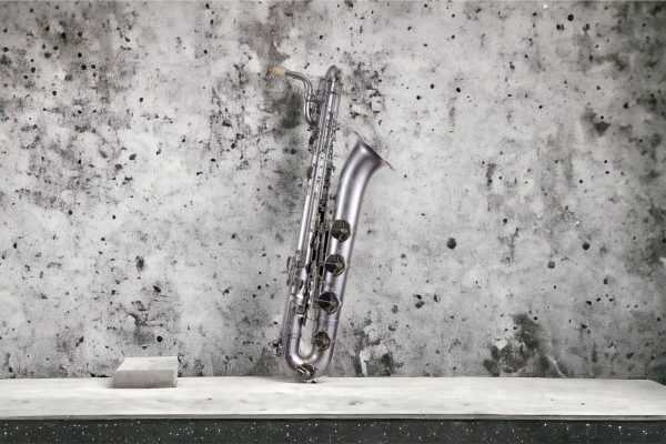 A silver saxophone elegantly leaning against a textured concrete wall, highlighting its classic design.