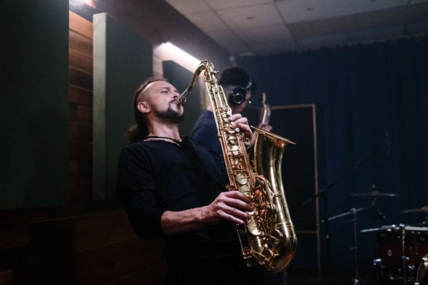 Musician playing saxophone passionately in an indoor recording studio setting.