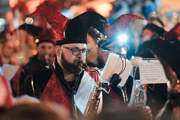 Musicians in festive costumes playing saxophones during Limassol Carnival at night.
