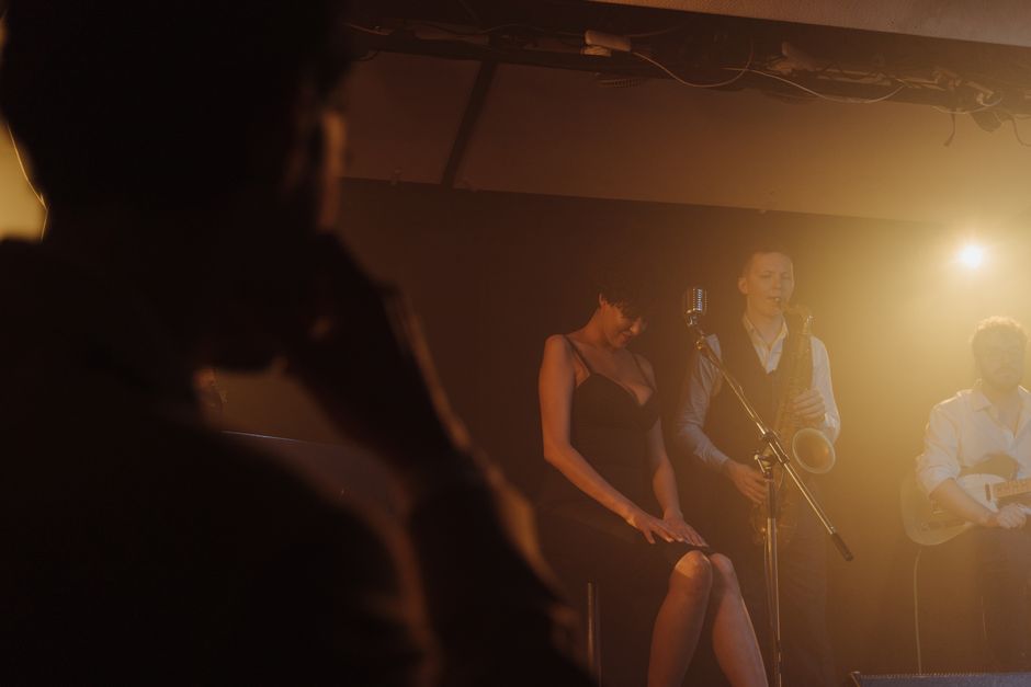 Intimate jazz performance featuring saxophone and vocals under moody lighting.