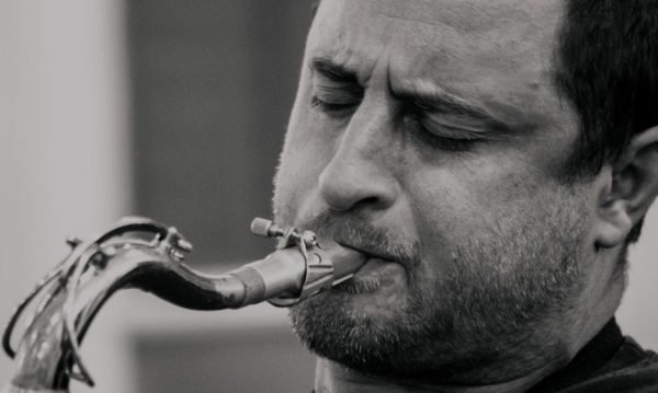 Close-up black and white portrait of a saxophonist passionately playing his instrument.