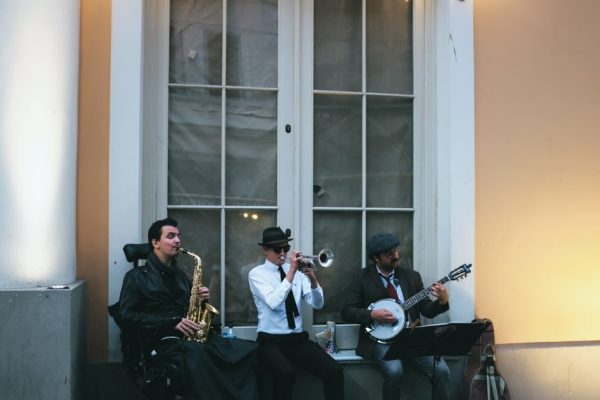 Three musicians play saxophone, trumpet, and banjo on the street, creating a vibrant jazz atmosphere.