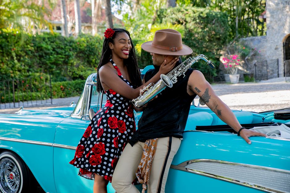 Happy couple with saxophone in vintage car, showcasing style and connection outdoors.