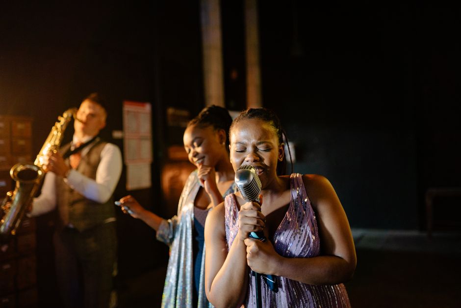 Live jazz performance featuring singers with vintage microphone and saxophonist.