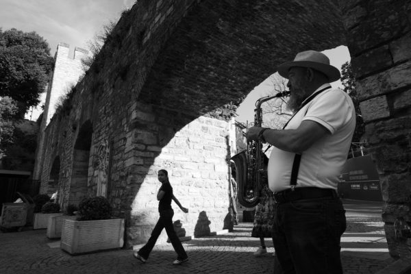 Black and white photo of a saxophonist performing under an ancient stone arch in Istanbul.