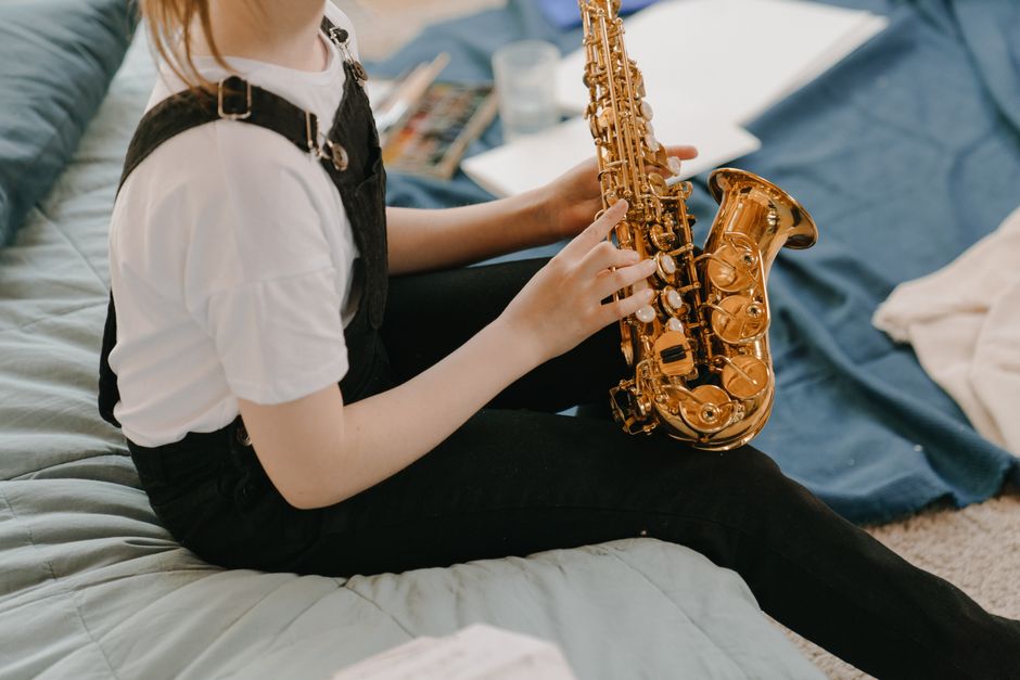 Young girl playing saxophone indoors, showcasing musical creativity in a relaxed environment.
