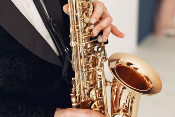 Close-up of a musician in a black suit playing a saxophone indoors, showcasing refined elegance.