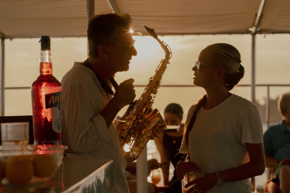 A saxophonist and woman enjoying a sunset on a boat in Venice.
