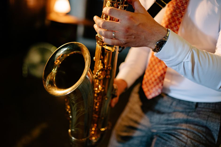 A man in a suit intricately playing a saxophone indoors, showcasing musical passion.