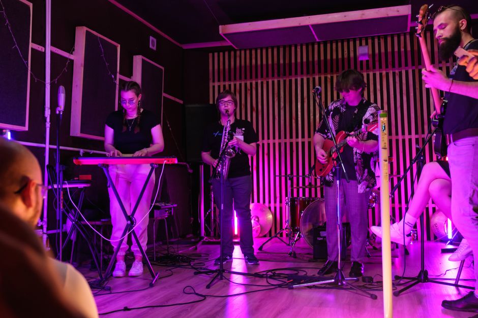 Energetic live band performing indoors with vibrant lighting in a small club setting.