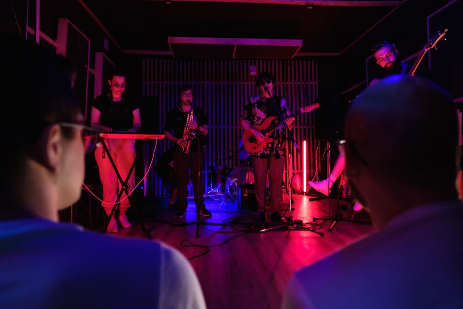 Dynamic live band performing in vibrant neon lighting with audience.