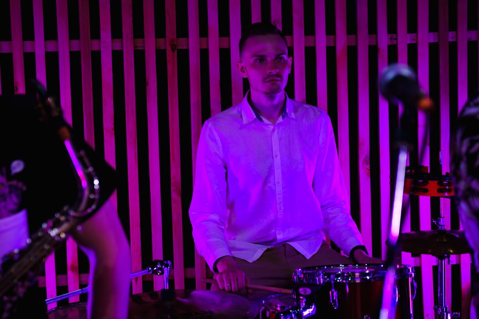 Drummer performing live at a concert with vibrant lighting.