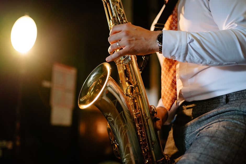 Close-up of a saxophonist performing, highlighting the brass instrument under warm lights.