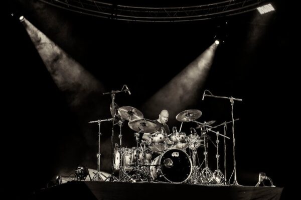 Dynamic concert scene with a drummer rocking on stage under spotlights in San Salvador.