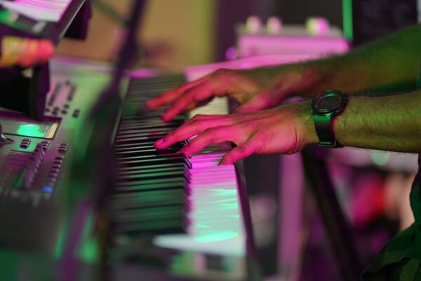 Vibrant close-up of a pianist's hands in purple lighting, capturing musical performance energy.