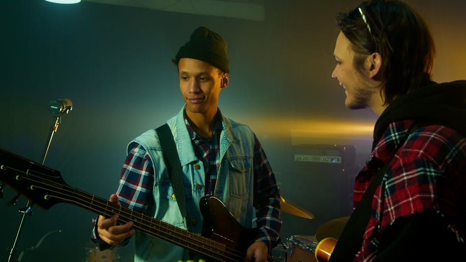Two young male musicians practicing in a rehearsal studio with electric bass guitar.