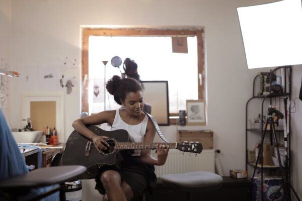 A young woman practicing guitar in a cozy indoor setting, expressing musical creativity.