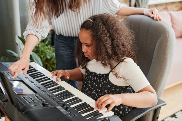 A young girl focused on learning piano during a music lesson with her teacher.