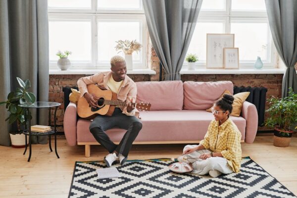 A father and daughter bonding over music in a cozy living room setting.