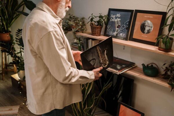 An elderly man explores a collection of vintage vinyl records in a cozy indoor setting.