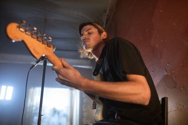 Dynamic indoor guitarist performance captured from a low angle, showcasing music passion.