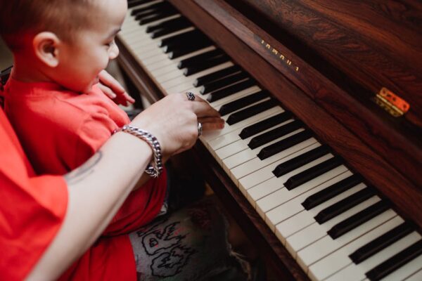 A joyful moment of a child learning piano with adult supervision, fostering musical growth.