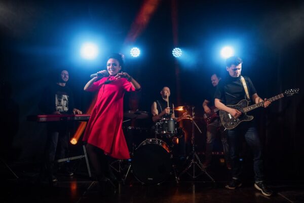 Vibrant live band performing on stage with various instruments under colorful stage lights.