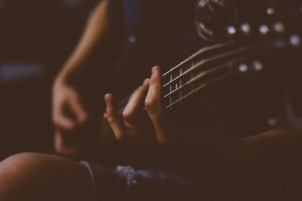 Moody close-up of a hand playing a guitar. Perfect for music-themed projects.