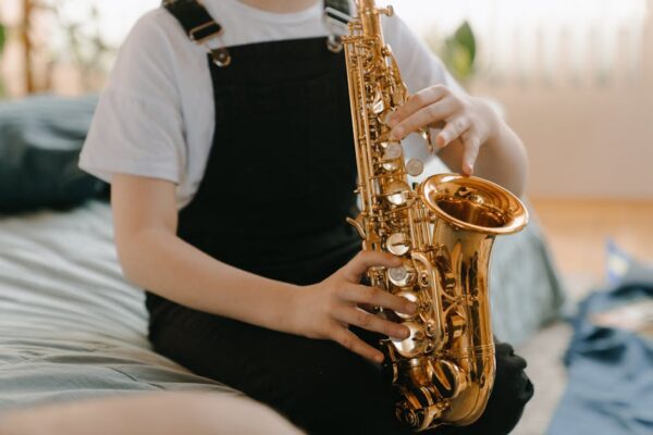 A young musician playing the saxophone indoors, focusing on musical expression.