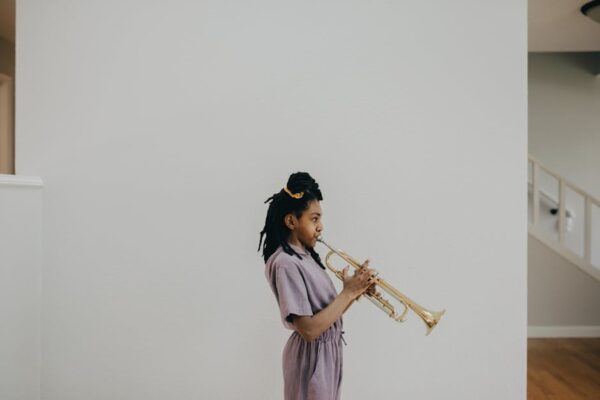 Side profile of a young girl playing the trumpet indoors with a minimalist background.