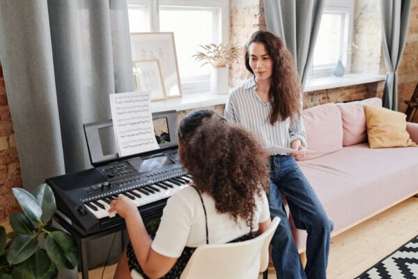 Adult woman teaching a child piano in a cozy room, fostering musical education.