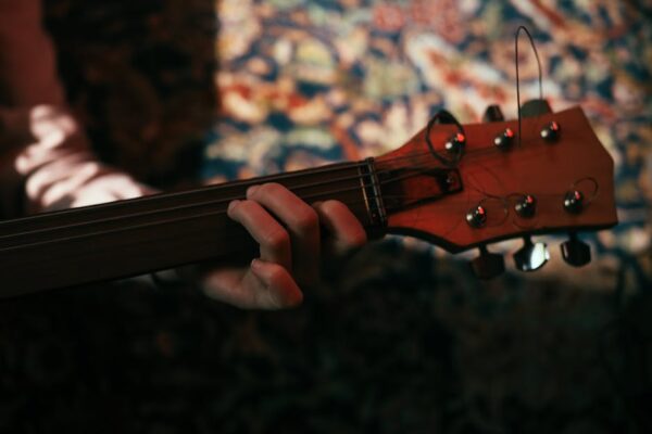 Artistic close-up of a musician's hand playing guitar strings on a colorful background.
