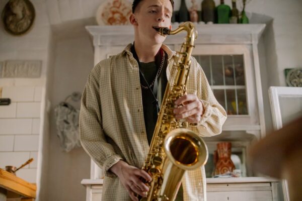 A young man passionately playing saxophone in a vintage kitchen setting.