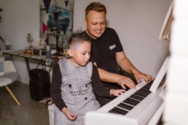 Father teaching his son to play piano in a cozy indoor setting, bonding through music.
