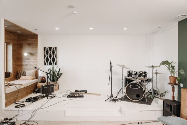 A modern music studio featuring a drum set, guitar, and cozy seating area for musicians.
