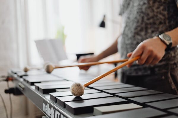 A man playing a xylophone indoors, focusing on his hands and mallets.