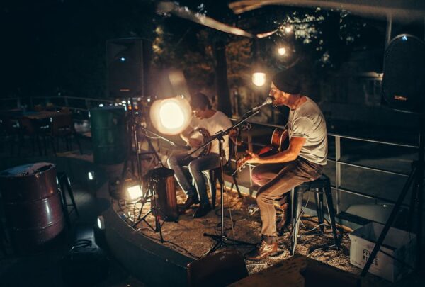 Two musicians performing acoustic music outdoors at night, illuminated by soft ambient lighting.