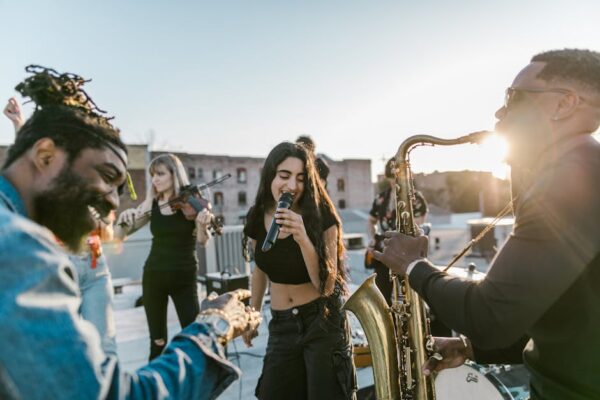 Energetic rooftop concert with diverse band playing at sunset, featuring saxophone and violin.