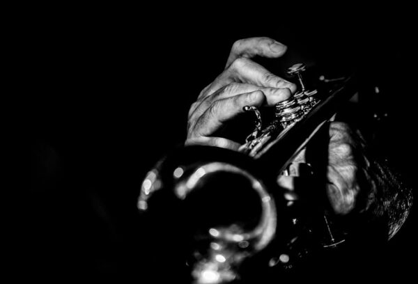 Black and white image of a musician's hands playing the trumpet during a live jazz performance.