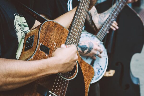 Close-up of musicians strumming acoustic and banjo guitars in a vibrant street performance.