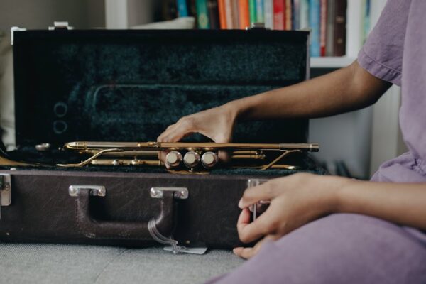 Close-up of hands with a brass trumpet on a case, indoors setting.
