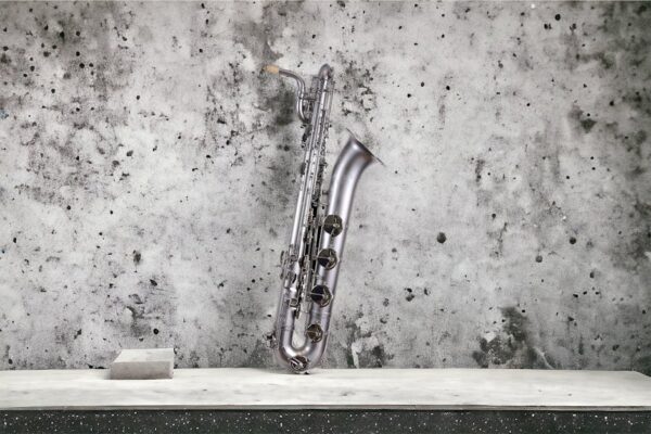 A silver saxophone elegantly leaning against a textured concrete wall, highlighting its classic design.