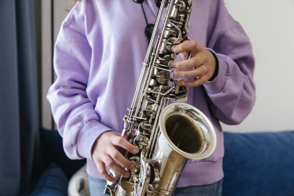 Close-up of a woman playing the saxophone indoors in a casual purple sweater.